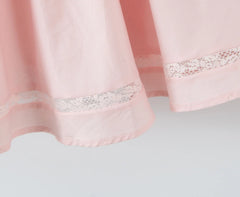 Close-up of a pink curtain with lace trim on a light gray background