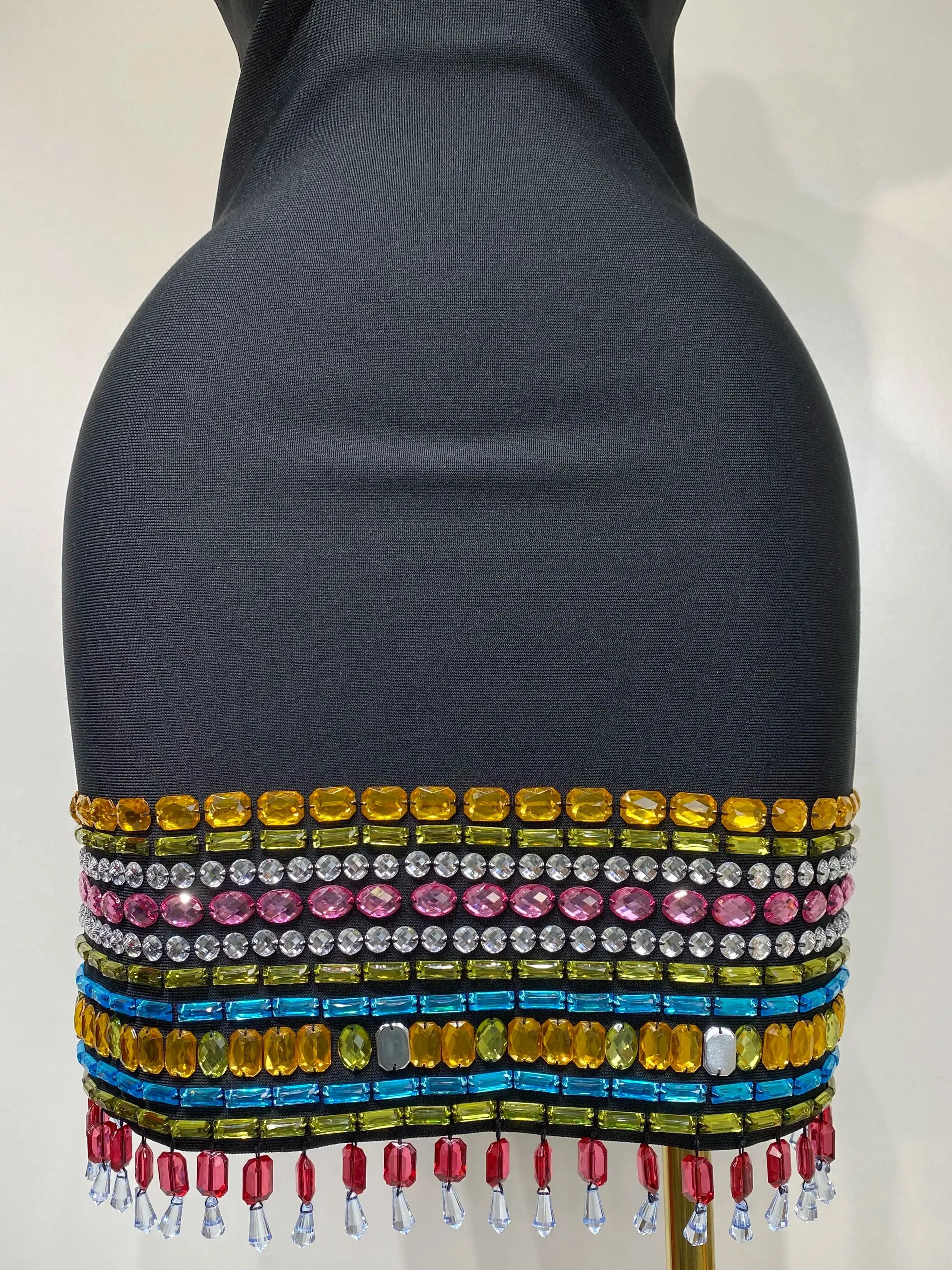 Mannequin wearing a colorful beaded top with a plain background