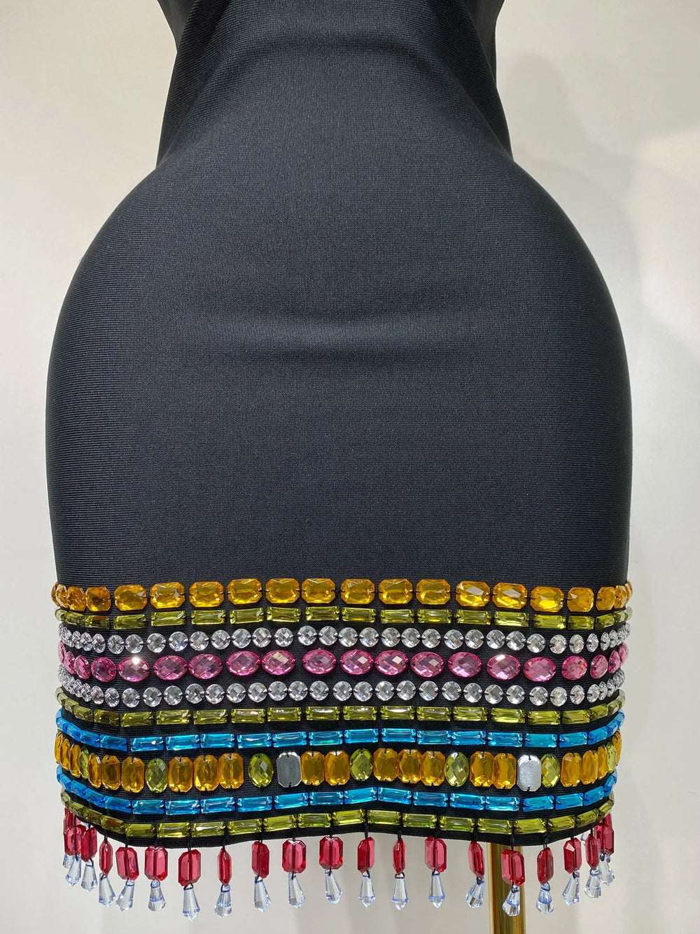Mannequin wearing a colorful beaded top with a plain background