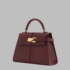 Maroon handbag with gold hardware on a white background