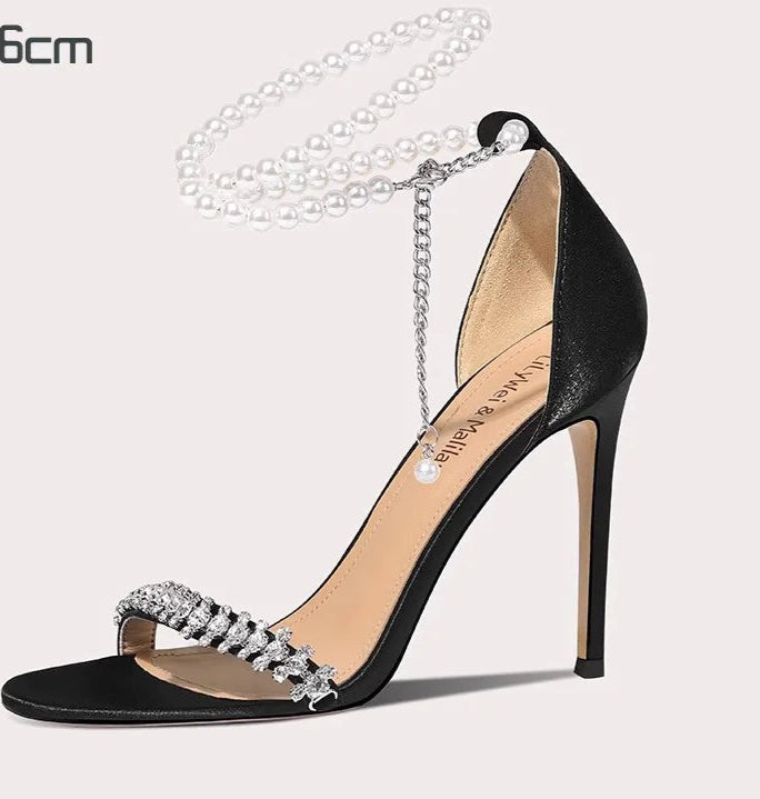 Black high-heeled sandal with crystal embellishments on a light gray background