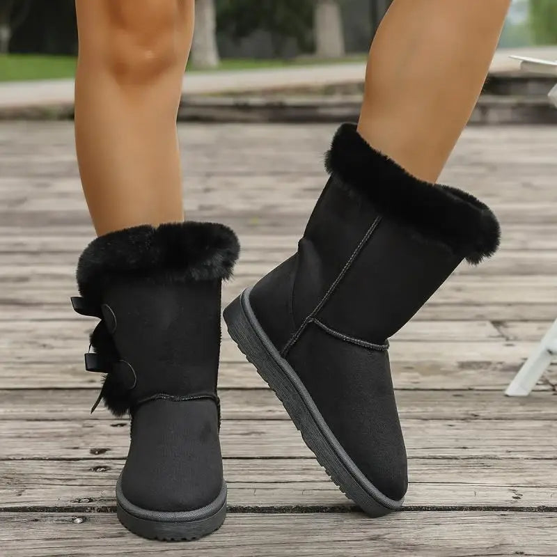 Black winter boots with fur trim on a wooden deck