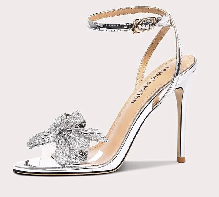 High-heeled sandal with clear strap and decorative bow on a white background