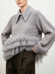 Gray knit sweater with a structured collar and a layered gray tulle ruffle detail at the waist, shown from the side.