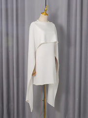 White poncho on a mannequin against a gray curtain background