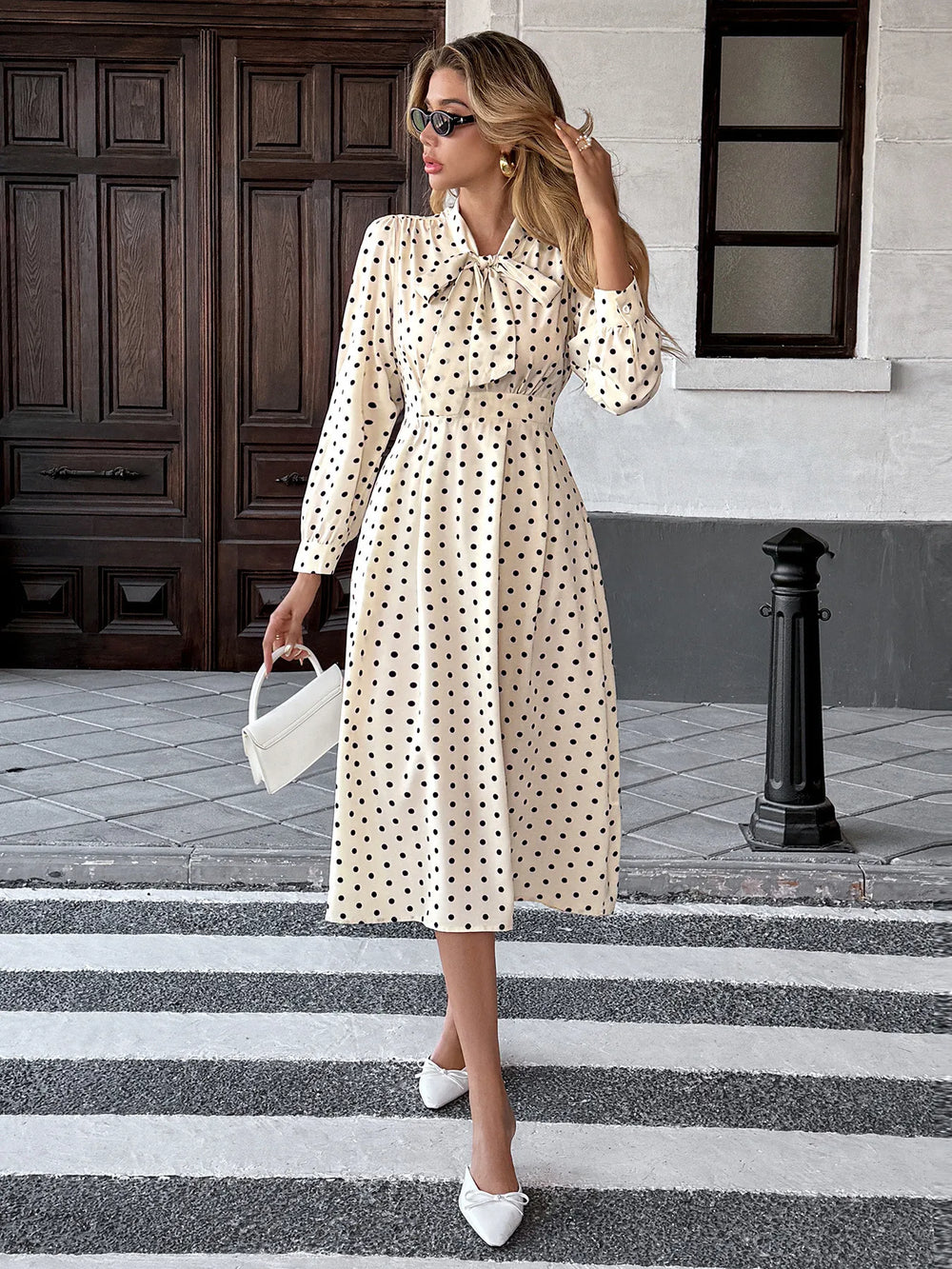 Woman in a polka dot dress crossing a zebra crossing.