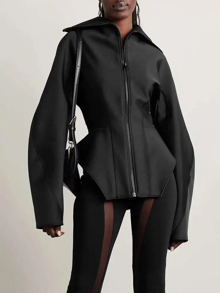 Person wearing a black jacket with a unique design on a plain background