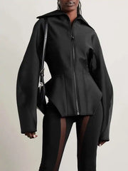 Person wearing a black jacket with a unique design on a plain background