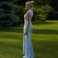 Woman in a light blue evening gown standing on grass with trees in the background