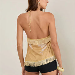 Woman wearing a beige halter top with fringe details and black shorts on a plain background