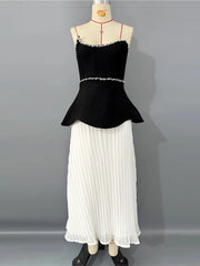 Black top and white pleated skirt on a mannequin against a gray background