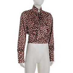 Close-up of satin fabric showing gentle sheen, printed dots, and sleeve cuff structure.