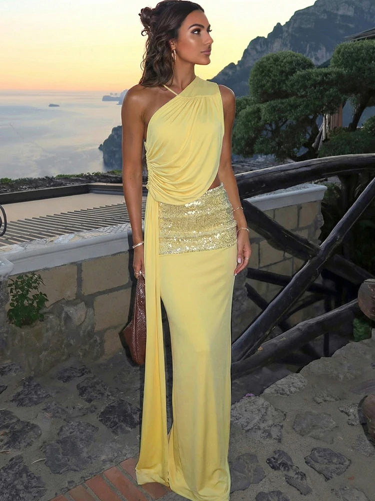 Woman in a yellow evening gown with a sequined skirt standing on a scenic balcony.