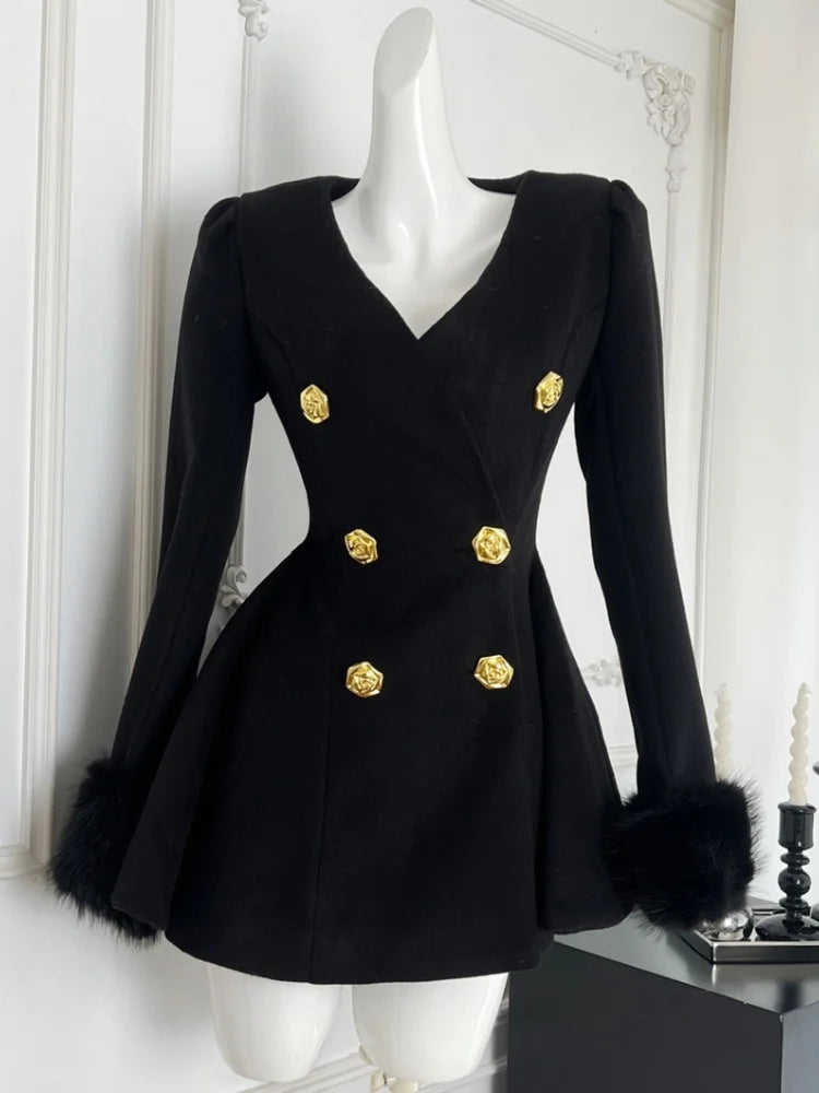 Black coat with gold buttons and fur cuffs on a mannequin against a white wall.