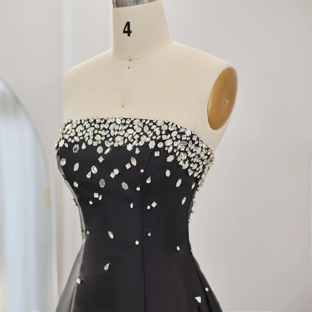 Black dress with white embellishments on a mannequin against a plain background
