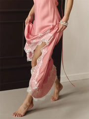 Person wearing a pink satin robe with lace trim, standing indoors.
