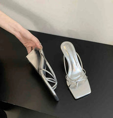 Silver high-heeled shoes on a black surface with a neutral background