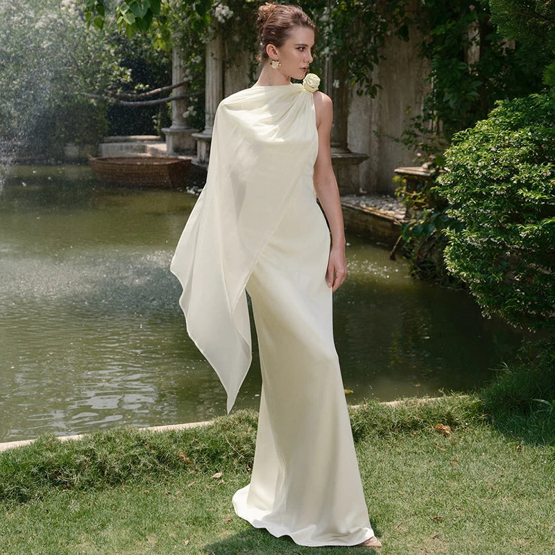 Woman in a white dress standing by a pond with greenery around