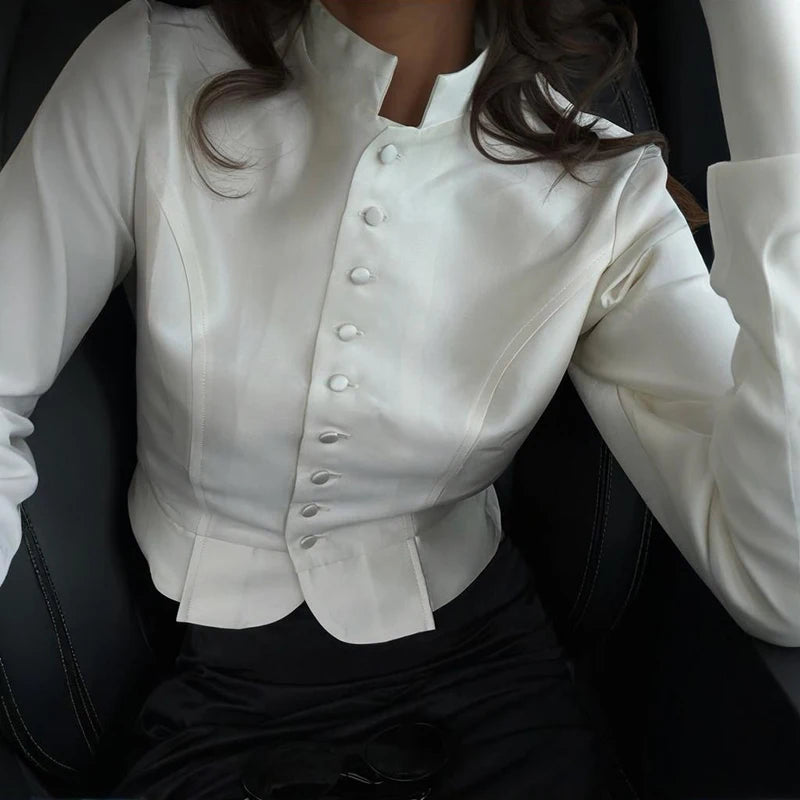 Person wearing a white blouse with puffed sleeves and buttons, sitting in a vehicle.