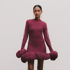 Woman wearing a burgundy dress with a unique skirt design on a plain background