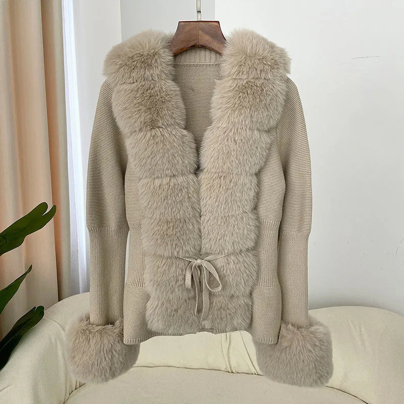 Beige sweater with fur vest on a hanger against a white wall.