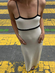 Person wearing a white dress with black straps on a yellow and black checkered floor.