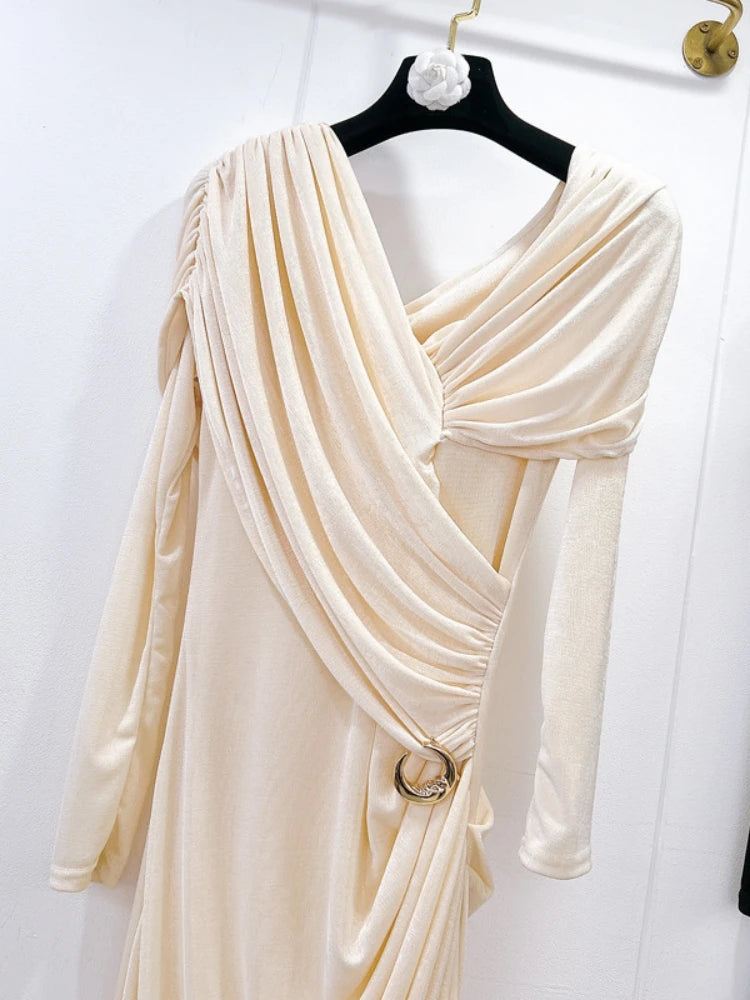 Beige draped dress on a hanger against a white background
