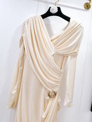 Beige draped dress on a hanger against a white background