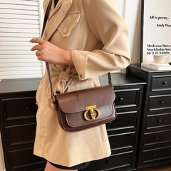 Person wearing a beige trench coat holding a brown handbag with a gold clasp.