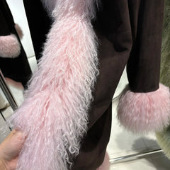 Close-up of pink fluffy scarf and gloves held by a person.