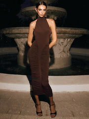 Woman in a brown dress standing in front of a fountain at night