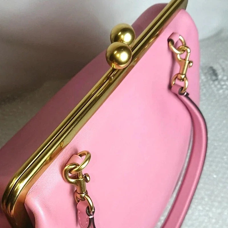 Close-up of a pink handbag with gold clasp and chain strap.