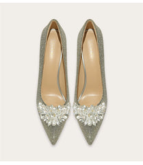 Pair of glittery high-heeled shoes with crystal embellishments on a light gray background