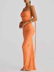 Orange evening gown with a long train on a plain background