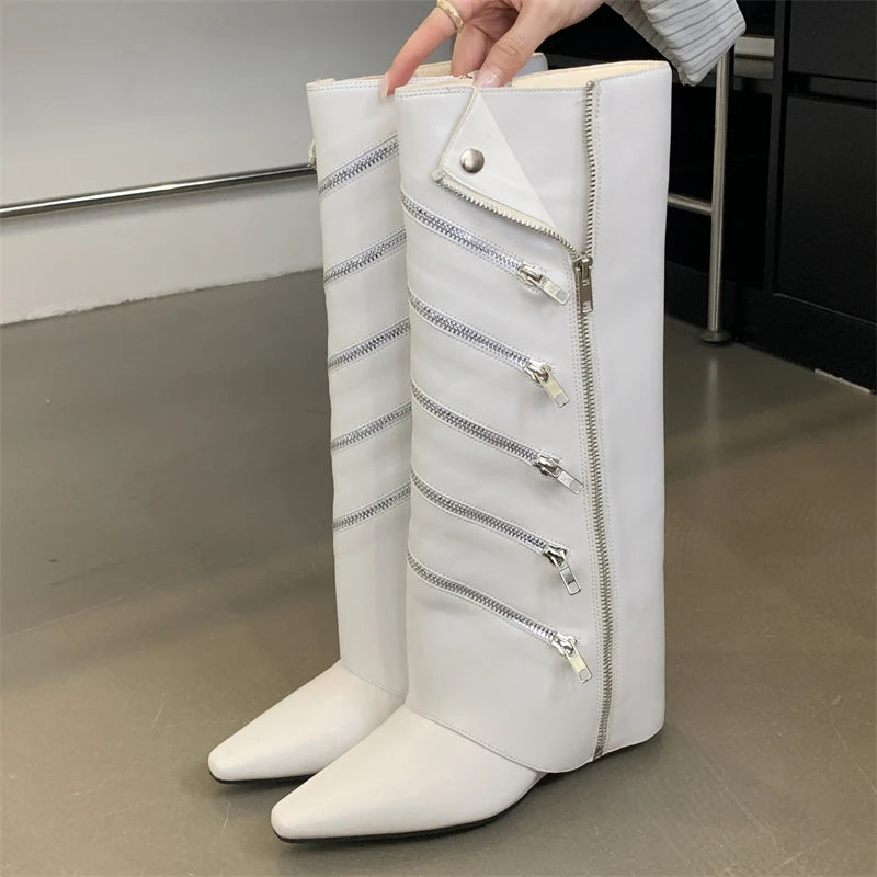 White knee-high boots with zippers held by a hand on a neutral background