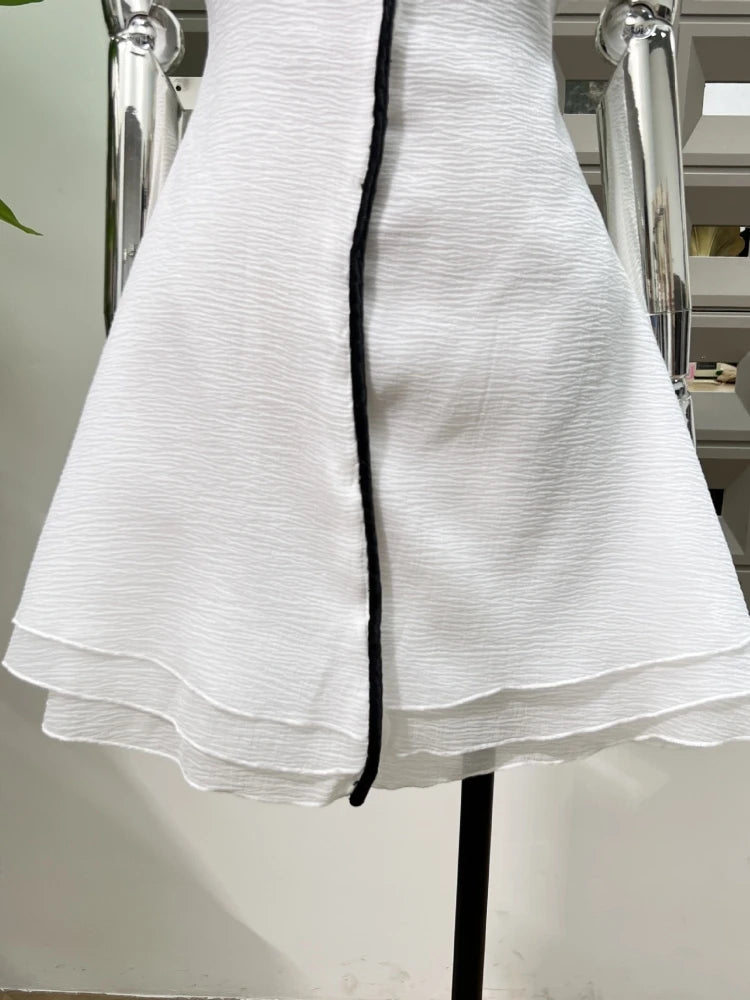 White dress with black trim on a mannequin against a neutral background