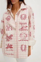 Person wearing a white shirt with red graphic designs on a plain background