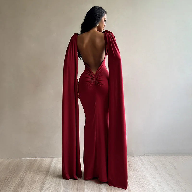 Woman wearing a red evening gown with a cape in a minimalistic setting