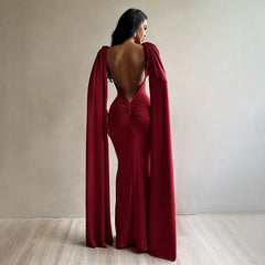 Woman wearing a red evening gown with a cape in a minimalistic setting