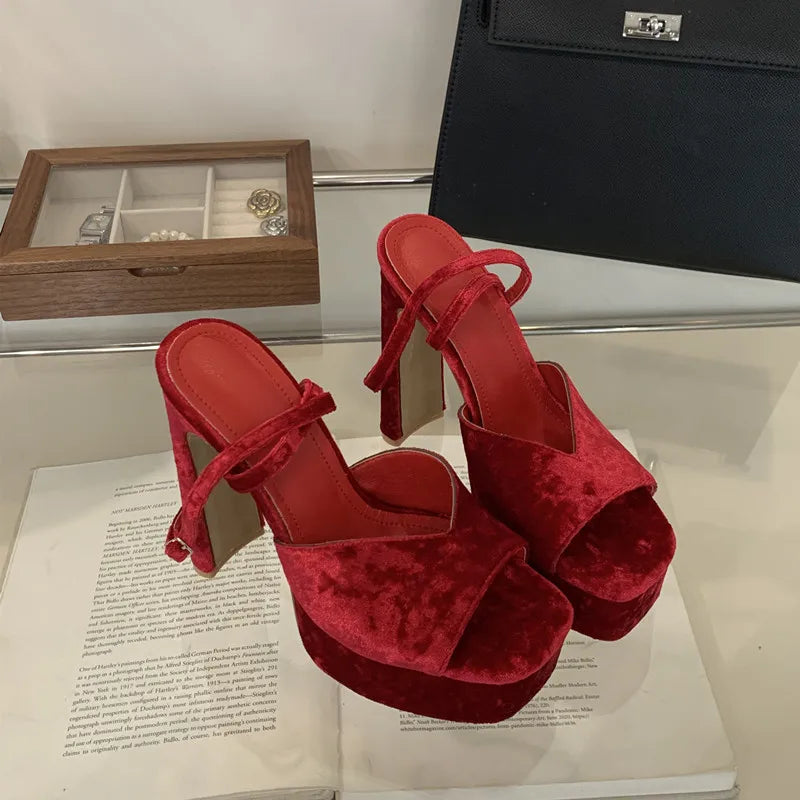 Red high-heeled shoes on an open book with a wooden jewelry box in the background.