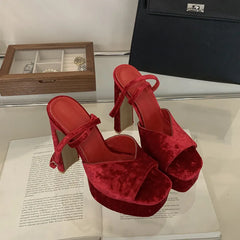 Red high-heeled shoes on an open book with a wooden jewelry box in the background.