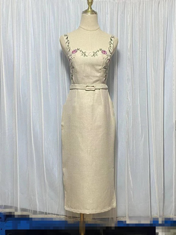 Beige dress with floral embroidery on a mannequin against a white curtain background