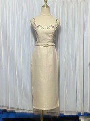 Beige dress with floral embroidery on a mannequin against a white curtain background