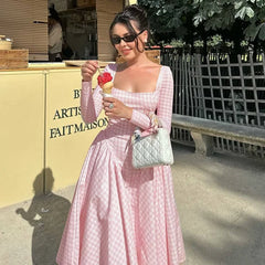 Woman in a pink dress holding a ice cream cone and a handbag, standing outdoors.