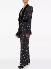 Side view of a model in a black star embroidered blazer with feather cuffs and flare pants.