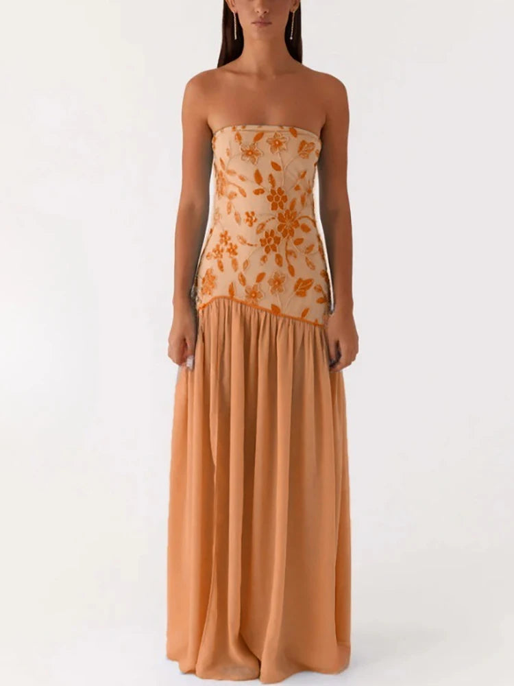 Woman wearing a strapless dress with floral top and solid bottom on a white background