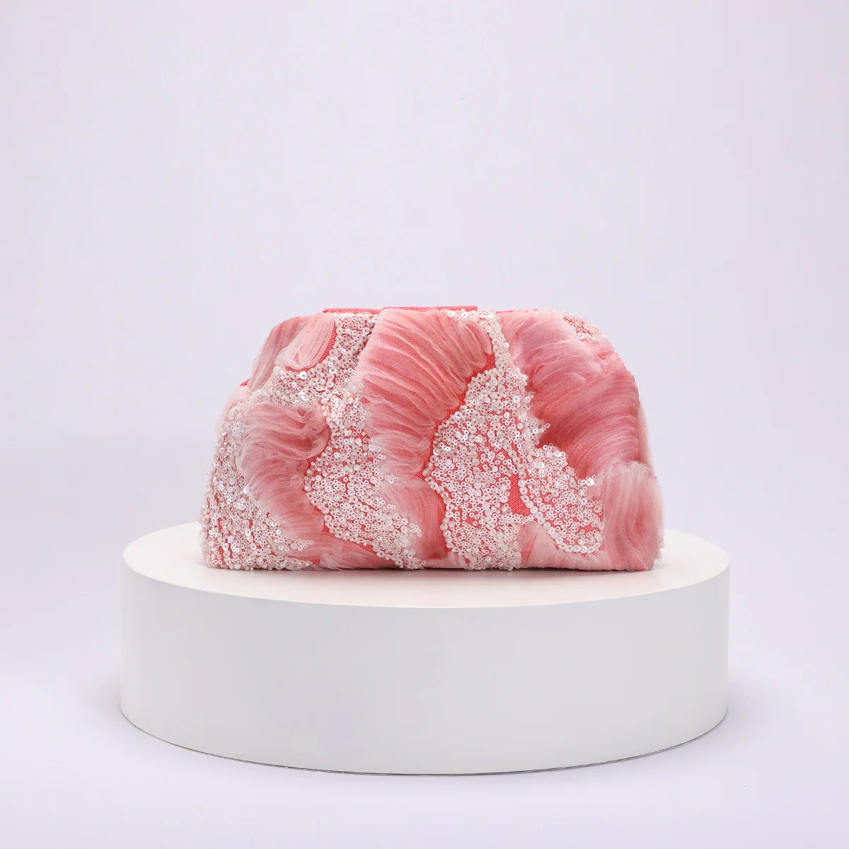 Pink and white marbled object on a white platform with a light gray background