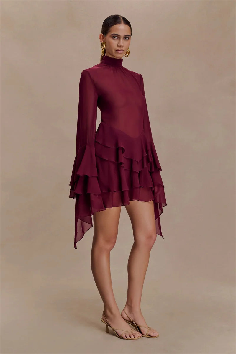 Woman wearing a burgundy dress with ruffled layers on a beige background
