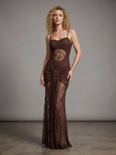 Woman wearing a brown evening gown with lace detailing against a gray background