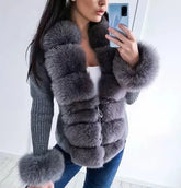 Person wearing a gray fur coat taking a mirror selfie.